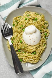 Delicious spaghetti with burrata cheese, peas and pesto sauce on light grey table, top view