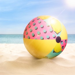 Colorful beach ball on sandy coast near sea