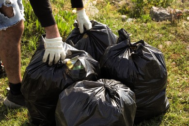 Man with trash bags full of garbage outdoors, closeup. Environmental Pollution concept