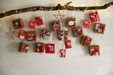 Handmade Advent calendar with gifts hanging on white wall. Christmas season