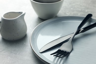 Stylish empty dishware and cutlery on light grey table, closeup