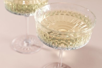 Photo of Glasses of expensive white wine on pink background, closeup