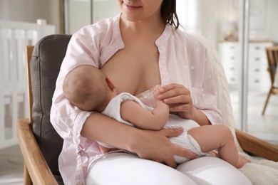 Young woman breastfeeding her little baby at home, closeup