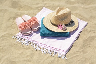 Photo of Stylish beach accessories and flower on sand outdoors