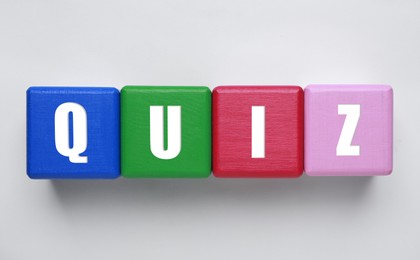 Colorful cubes with word Quiz on white background, top view