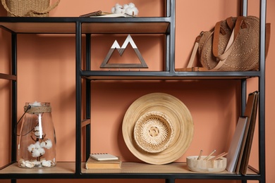 Photo of Stylish shelving unit with decorative elements near color wall. Interior design