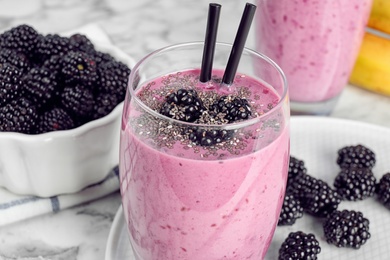 Delicious blackberry smoothie in glass on marble table, closeup