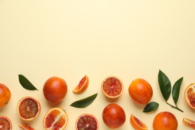 Many ripe sicilian oranges and leaves on beige background, flat lay. Space for text