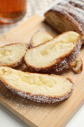 Photo of Pieces of delicious yeast dough cake on wooden board, closeup