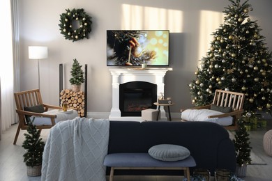 Modern TV set on light wall in room decorated for Christmas
