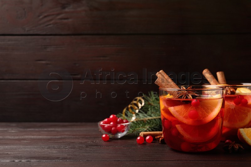 Delicious punch drink with cranberries and orange on wooden table. Space for text