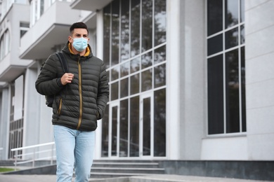 Man in medical face mask walking outdoors. Personal protection during COVID-19 pandemic
