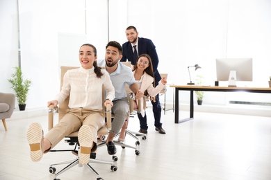 Office employees riding chairs at workplace. Space for text