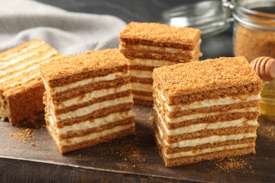 Photo of Delicious layered honey cake on wooden board, closeup
