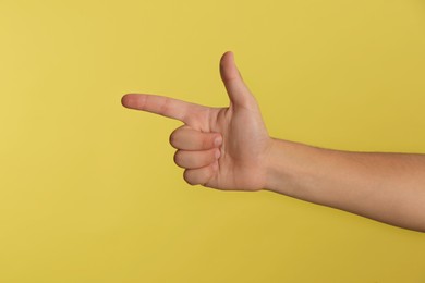 Teenage boy pointing at something on yellow background, closeup