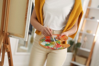 Young woman drawing on easel at home, closeup