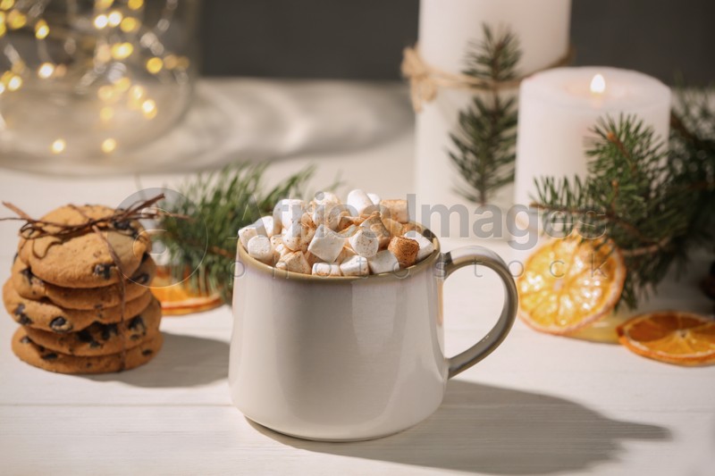 Cup of hot drink with marshmallows and cookies on white table