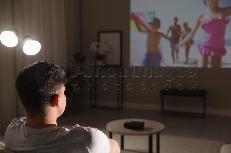 Man watching movie on sofa at night, back view. Space for text