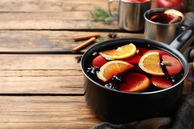 Delicious mulled wine and ingredients on wooden table. Space for text