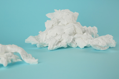 Used paper tissues on light blue background, closeup