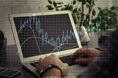 Forex trading. Man working with laptop at table and chart, closeup