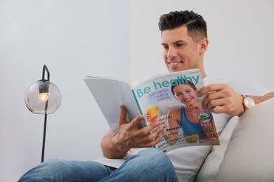Photo of Man reading magazine on sofa in living room