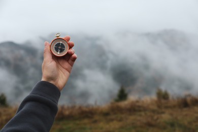 Woman using compass during journey in mountains, closeup. Space for text