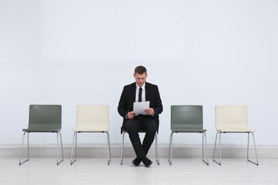 Man with papers waiting for job interview in office hall