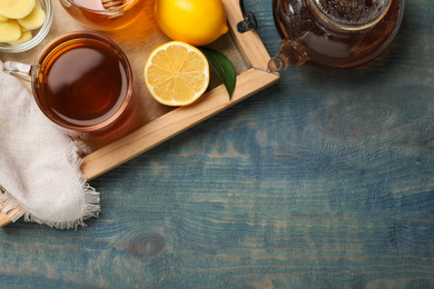 Delicious tea with honey, ginger and lemon on blue wooden table, top view. Space for text