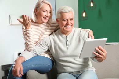 Mature couple using video chat on tablet at home