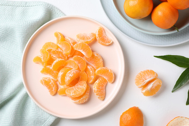 Photo of Segments of fresh juicy tangerines on white table, flat lay