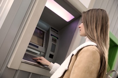 Photo of Young woman entering cash machine pin code outdoors