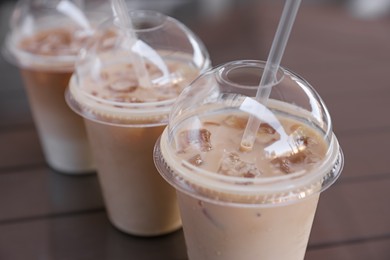 Photo of Plastic takeaway cups of delicious iced coffee on table, closeup