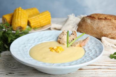 Delicious corn cream soup served on white wooden table