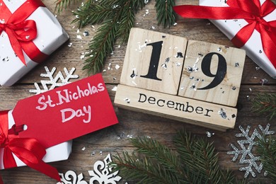 Saint Nicholas Day. Block calendar with date December 19, festive decor and gift boxes on wooden table, flat lay