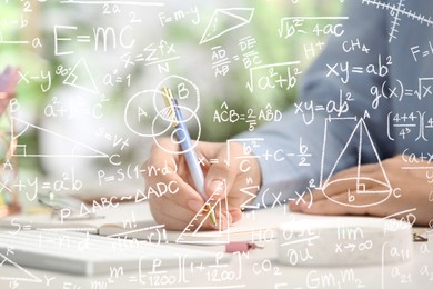 Science and education concept. Illustration of basic physics and mathematics formulas and woman working at table, closeup