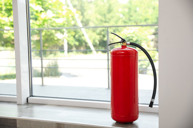 Fire extinguisher near window indoors. Space for text