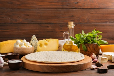 Pizza crust and fresh ingredients on wooden table