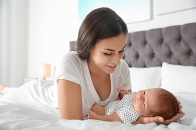 Young woman with her newborn baby on bed