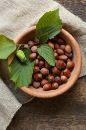 Tasty hazelnuts and green leaves on wooden table, top view. Healthy snack