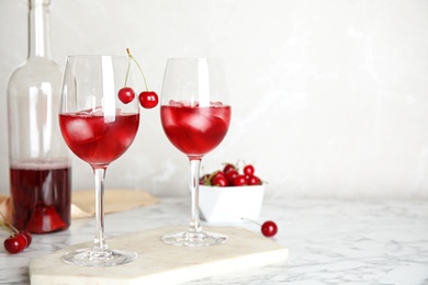 Delicious cherry wine with ripe juicy berries on white marble table. Space for text