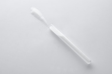 Glass tube with salt on white background, top view