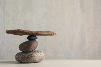 Stack of stones with tree branch on wooden table, space for text. Harmony and balance concept