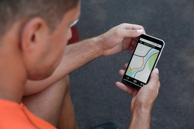 Man using fitness app on smartphone outdoors, closeup