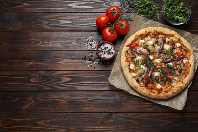Photo of Tasty pizza with anchovies and ingredients on wooden table, flat lay. Space for text