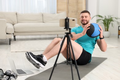 Photo of Trainer with ball streaming online workout on phone at home