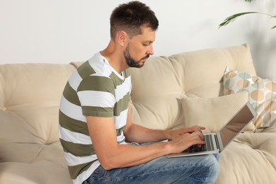 Man with poor posture using laptop on sofa at home