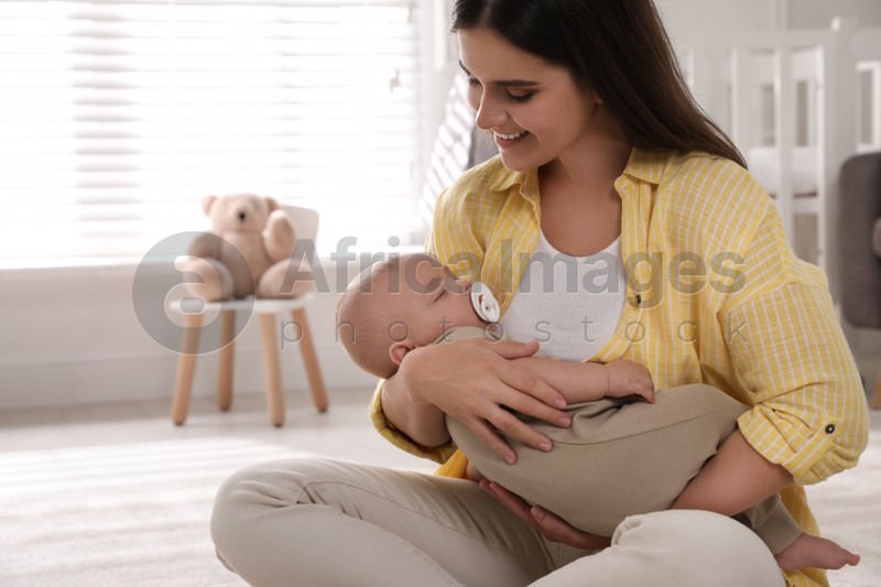 Photo of Young woman with her sleeping baby on floor at home