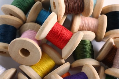 Pile of wooden spools with colorful sewing threads, closeup