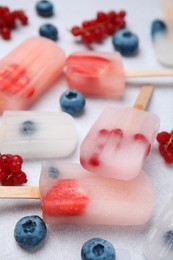 Photo of Tasty berry ice pops on light table, closeup